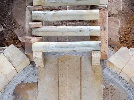 Detail showing the two sillimanite brick offcuts acting as stops for the first firebar. These will be concreted in position.