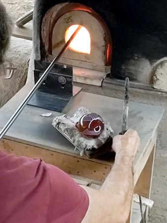 Turning the vessel whilst heating the blowing iron to make the punty