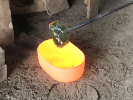 Removing pots on the final day before shutting down the furnace - note the use of a rectangle of cold glass on a bit iron to lift the pot (Photo © Fiona Rashleigh)