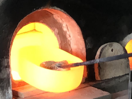 Removing pots on the final day before shutting down the furnace - note the use of a rectangle of cold glass on a bit iron to lift the pot (Photo © Fiona Rashleigh)